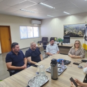 A imagem mostra a Presidente Baretta, a Prefeita de Minas do Leão, Silvia Lasek,  Vice-Prefeito Daniel Oliboni, acompanhados de sua equipe, em uma reunião. Todos estão sérios e em um ambiente de trabalho, com mesas e cadeiras. A atmosfera é de colaboração e diálogo, refletindo o fortalecimento de laços institucionais entre os participantes. 