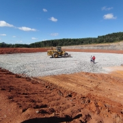 A imagem mostra a construção das Estações de Tratamento de Efluentes (ETEs) na região de Candiota. Em primeiro plano, um trator de grande porte está posicionado sobre uma área de terraplanagem. O fundo apresenta um panorama da área em desenvolvimento, com pode-se notar o início da estrutura das ETEs. O céu está limpo e há pouca vegetação ao redor, evidenciando o foco nas obras de infraestrutura. A cena transmite a ideia de progresso e melhorias na gestão de efluentes na região.