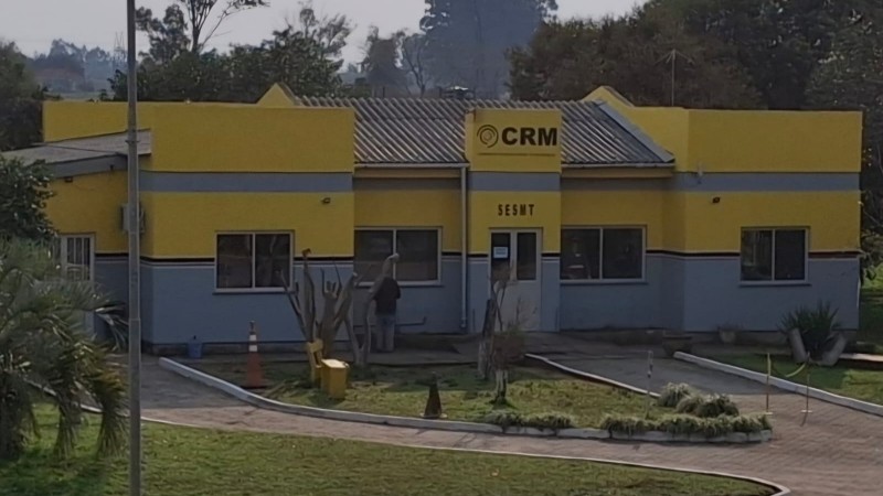 Fachada de uma empresa em processo de revitalização. A estrutura está passando por pintura e reforma geral. A cor predominante da fachada é amarela, com andaimes e materiais de obra visíveis, indicando que o prédio está ficando novo
