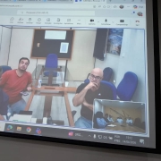 Na foto aparece 8 pessoas, dentre 3 numa tela maior e 5 numa tela menor, mostrando que est&atilde;o em reuni&atilde;o em formato h&iacute;brido falando de etapas para concluirem o EIA-RIMA em Candiota segundo as exig&ecirc;ncias da FEPAM. Todos est&atilde;o com o semblante s&eacute;rios e compenetrados na pauta. 
