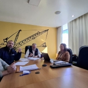 4 pessoas est&atilde;o numa sala ampla de olhos na tela, porque est&aacute; acontecendo a reuni&atilde;o de administra&ccedil;&atilde;o mensal. No momento apenas 1 est&aacute; falando e todos est&atilde;o prestando aten&ccedil;&atilde;o. A mesa &eacute; retangular e aparecem os 4 que est&atilde;o na sala da CRM