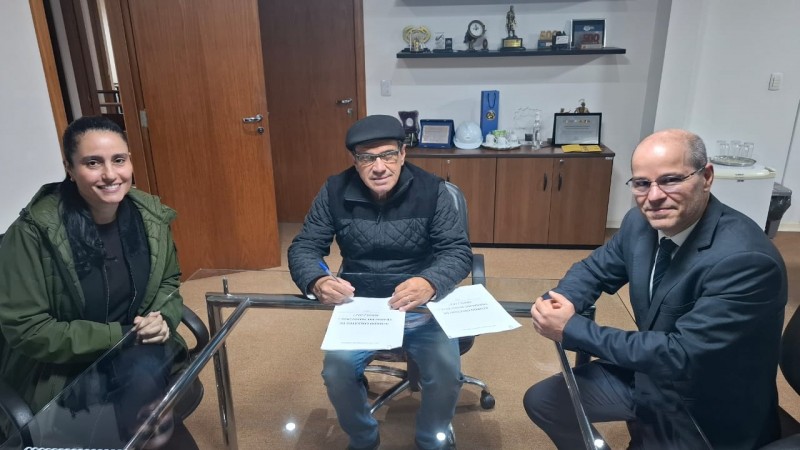Tr&ecirc;s pessoas assinando o acordo coletivo dos trabalhadores do sindicato olhando para a c&acirc;mera de forma conciliadora