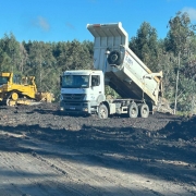 Na imagem aparece 2 m&aacute;quinas trabalhando para o processo de recupera&ccedil;&atilde;o ambiental em Minas do Le&atilde;o, um trator e uma escavadeira. O ch&atilde;o mostra carv&atilde;o sendo retirado a c&eacute;u aberto mostrando uma vegeta&ccedil;&atilde;o ao redor. 