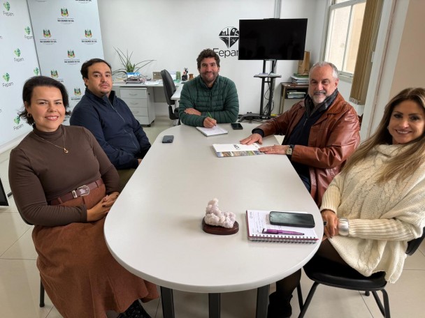 Na imagem tem 4 pessoas sentadas em uma reunião, todos olhando para a câmera com um sorriso largo e mostrando-se satisfeitos com a reunião. Na foto temos os diretor-presidente Ademir Baretta e o diretor técnico Murilo da Luz com as engenheiras e o diretor técnico Gabriel da FEPAM. 